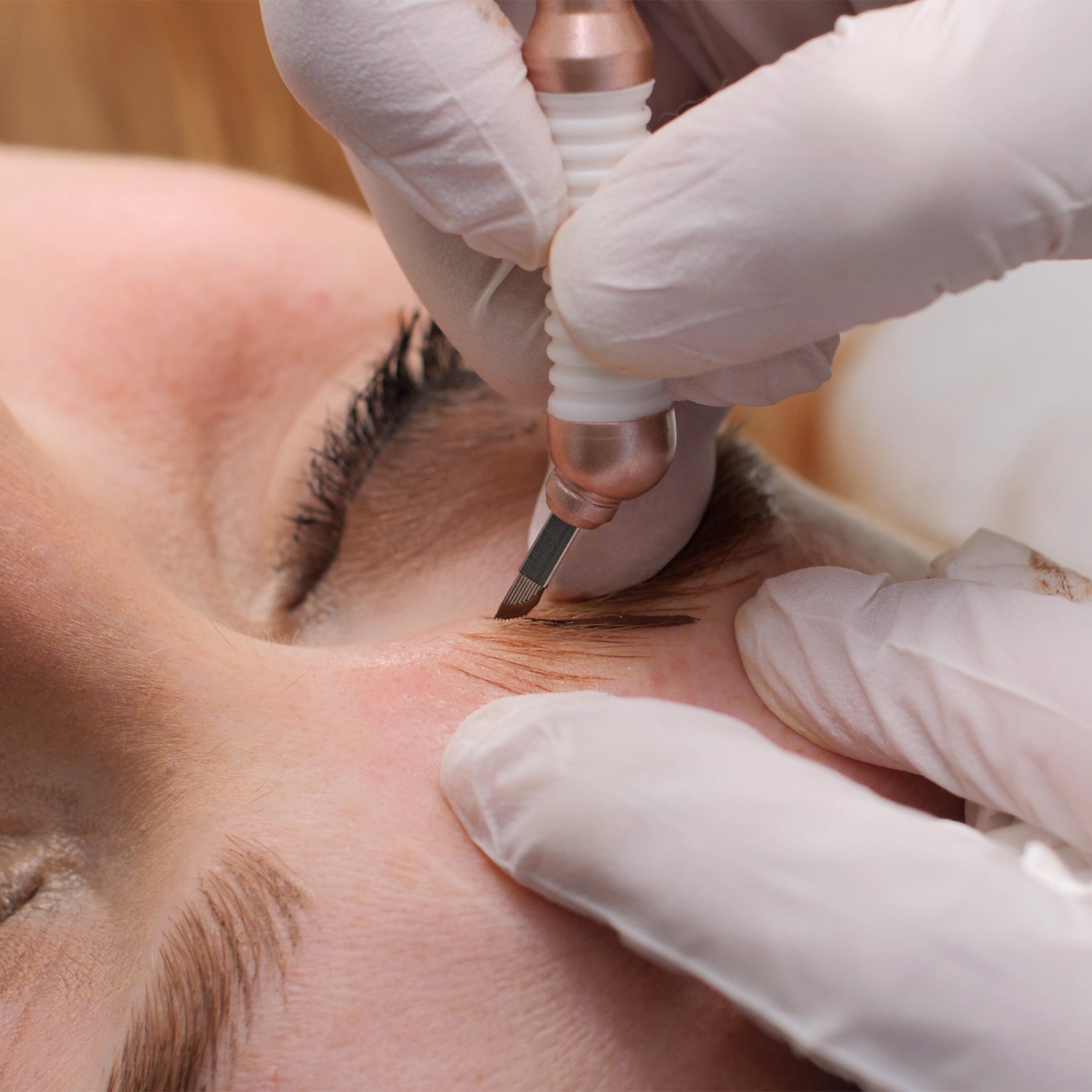 Close-up of microblading tool creating fine hair-stroke brows